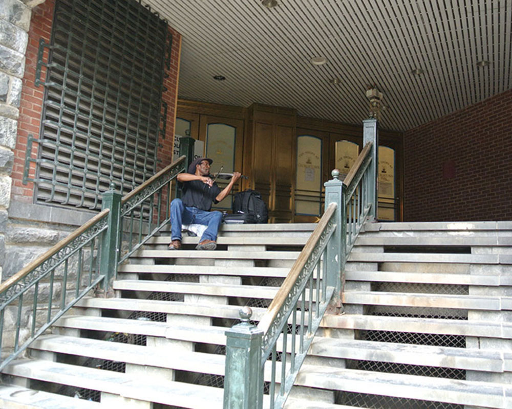 Violinist sitting on the steps of a Georgetown Store